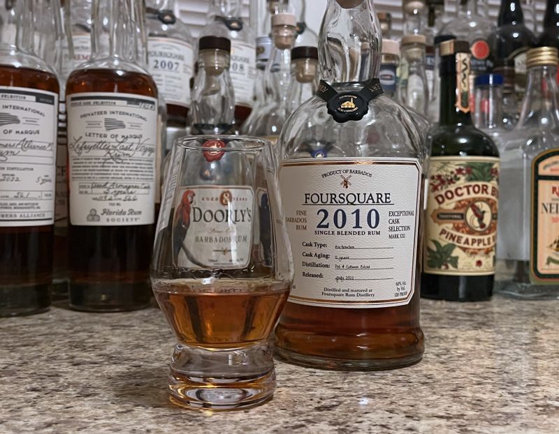 A bottle of Foursquare 2010 next to a glencairn of rum on a kitchen counter