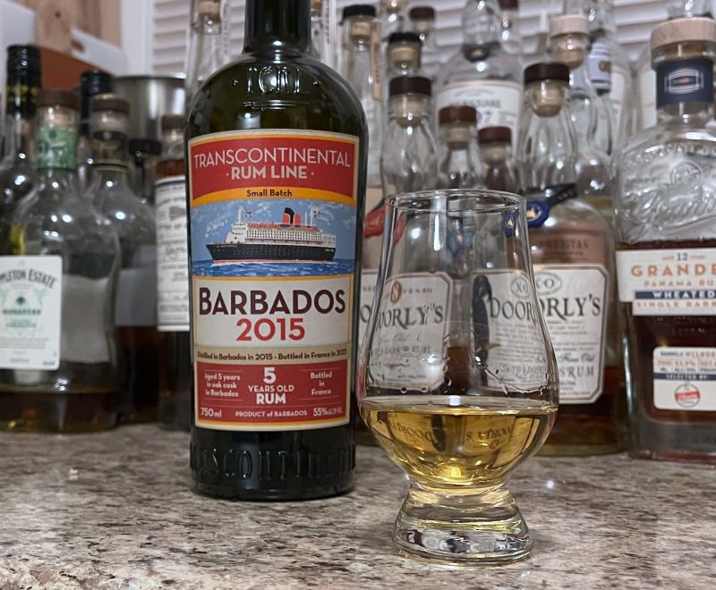 A bottle of TCRL Barbados 2015 next to a glencairn of rum on a kitchen counter