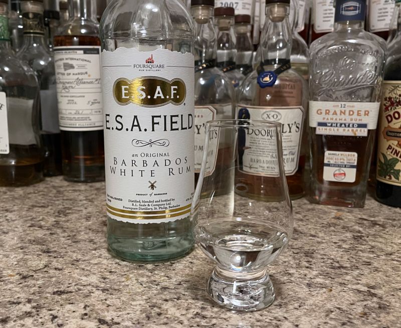 A bottle of E.S.A. Field next to a glencairn of rum on a kitchen counter