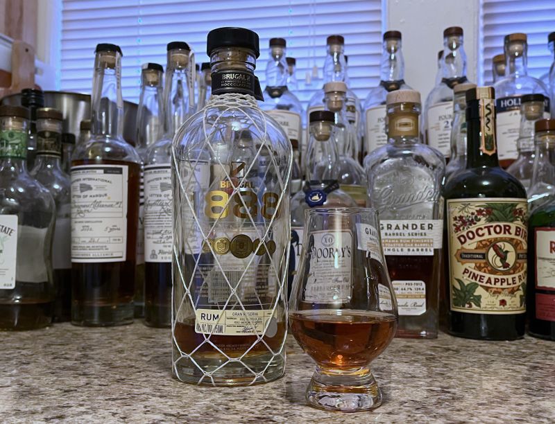A bottle of Brugal 1888 next to a glencairn of rum on a kitchen counter