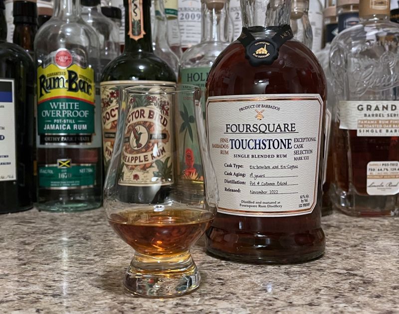 A bottle of Foursquare Touchstone next to a glencairn of rum on a kitchen counter
