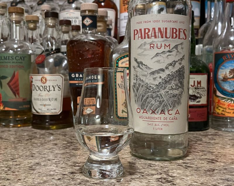 A bottle of Paranubes next to a glencairn of rum on a kitchen counter