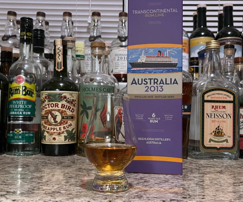A bottle of TCRL Australia 2013 next to a glencairn of rum on a kitchen counter