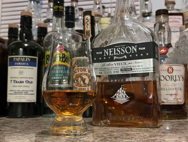 A bottle of Neisson Vieux next to a glencairn of rum on a kitchen counter