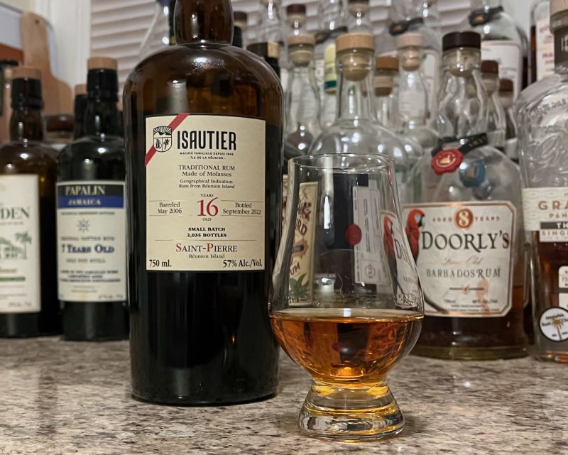 A bottle of Isautier 16 year Traditional next to a glencairn of rum on a kitchen counter