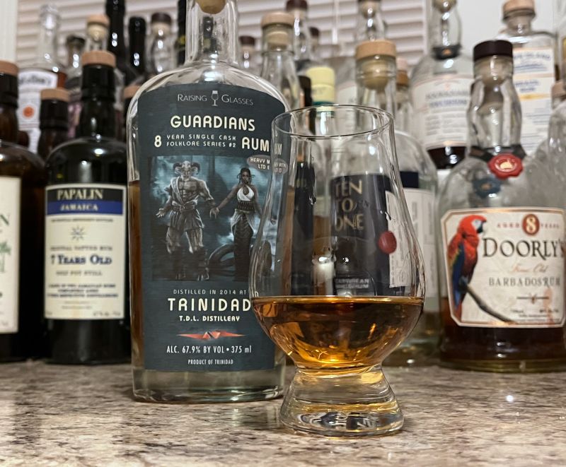 Raising Glasses Guardians bottle next to a glass of rum
