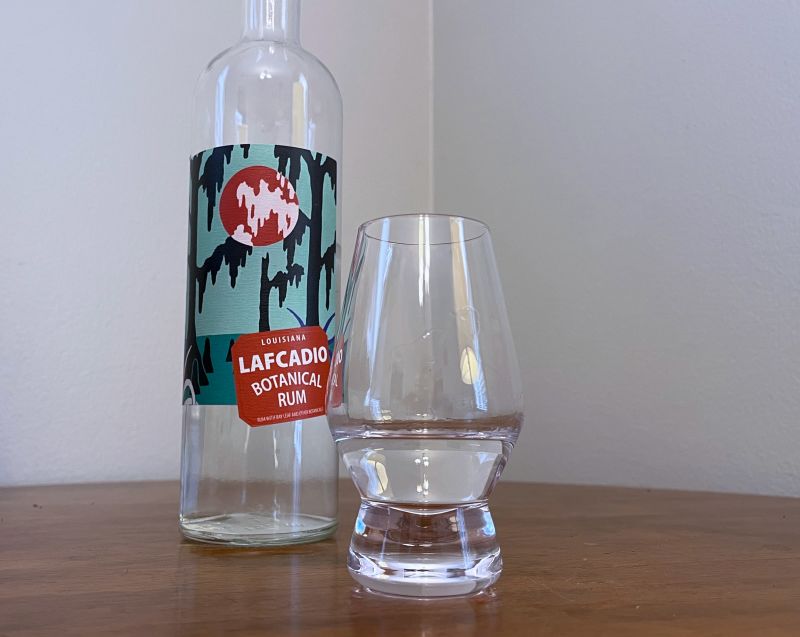 A bottle of Lafcadio Botanical Rum next to a glass of rum