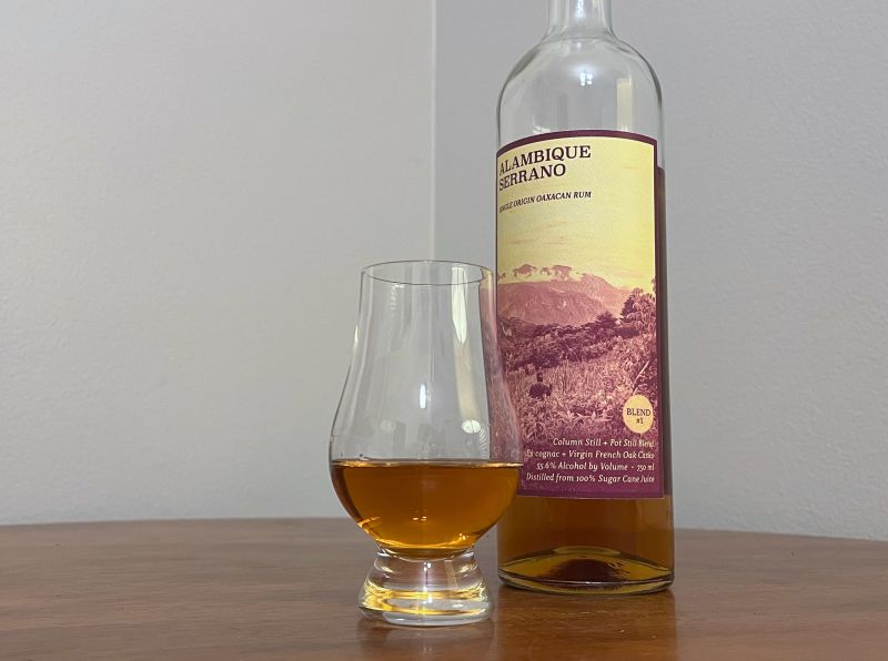 A bottle of Alambique Serrano Blend #1 next to a glass of rum