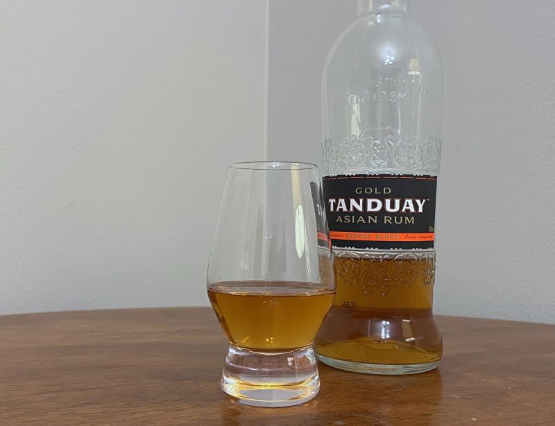 A bottle of Tanduay Gold Asian Rum next to a glass of rum