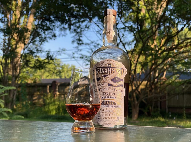 A bottle of Star Union Navy Strength Dark Rum next to a glass of rum