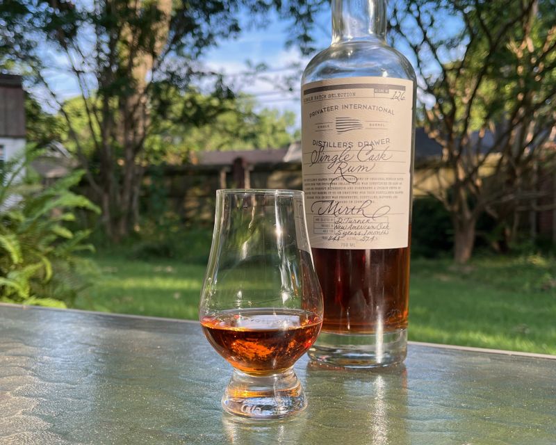 A bottle of Privateer Mirth next to a glass of rum