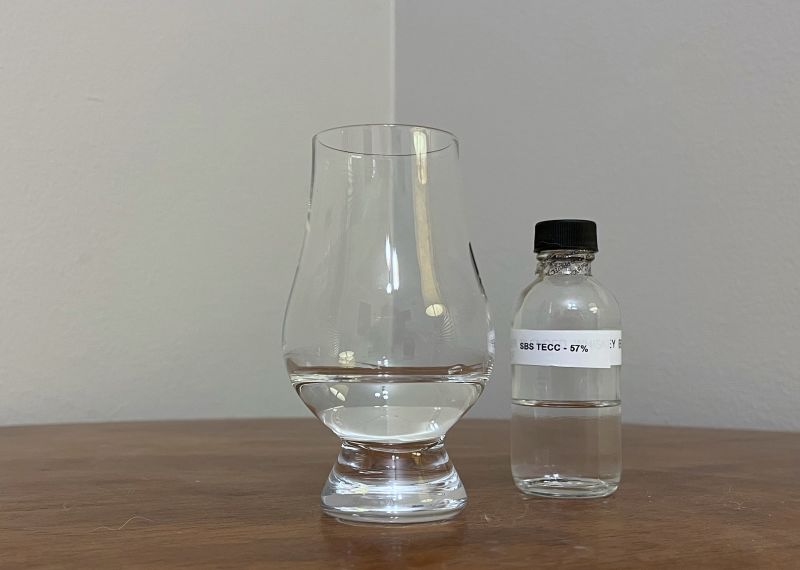 A bottle of S.B.S. Origins Jamaica TECC next to a glass of rum