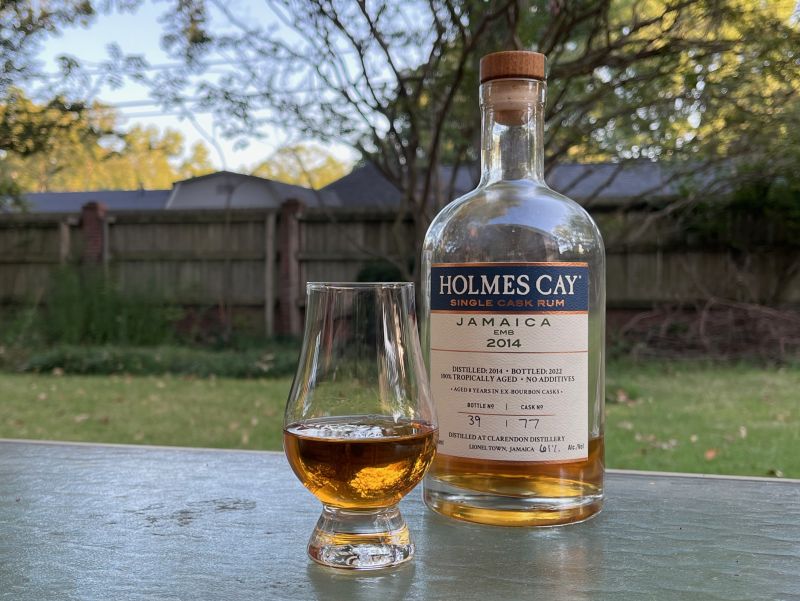 A bottle of Holmes Cay Jamaica EMB 2014 next to a glass of rum