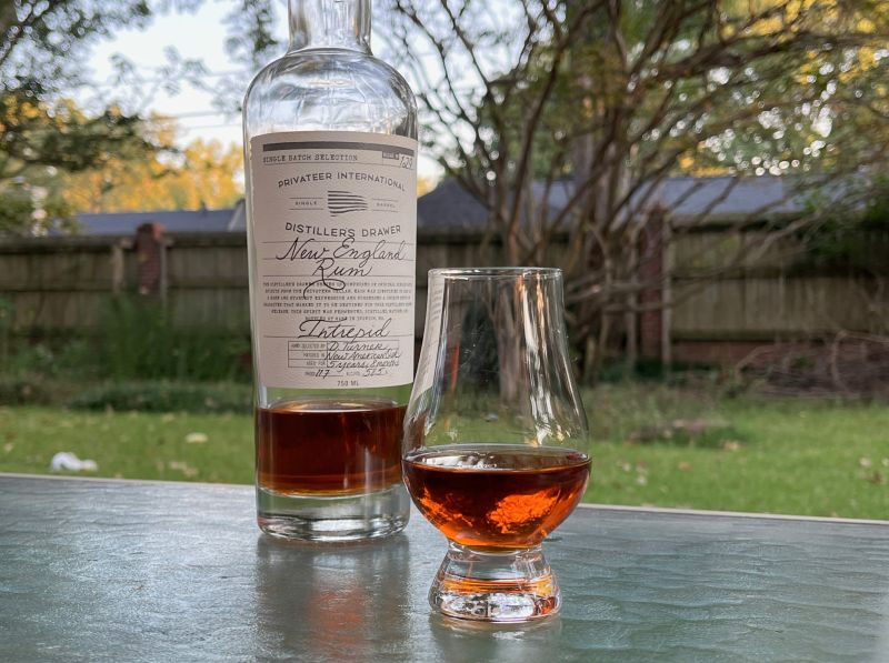 A bottle of Privateer Intrepid next to a glass of rum
