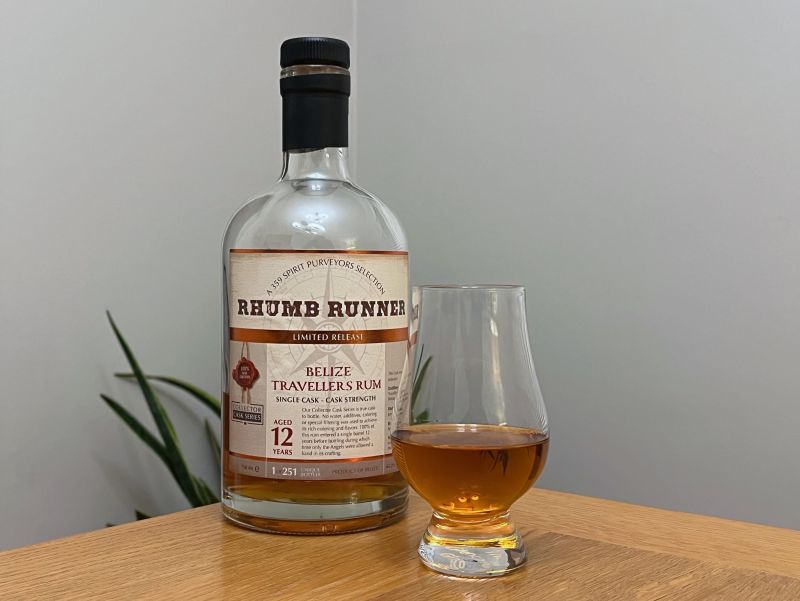 A bottle of Rhumb Runner Belize Travellers 12 year next to a glass of rum