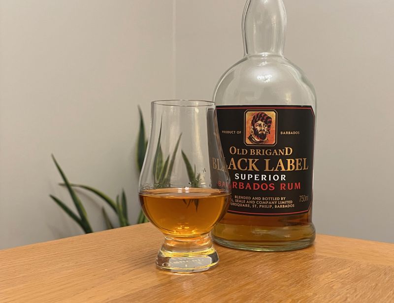 A bottle of Old Brigand Black Label next to a glass of rum