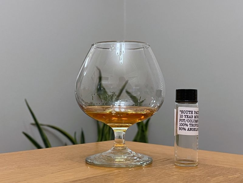 A bottle of Dead Reckoning South Pacific 10 year next to a glass of rum