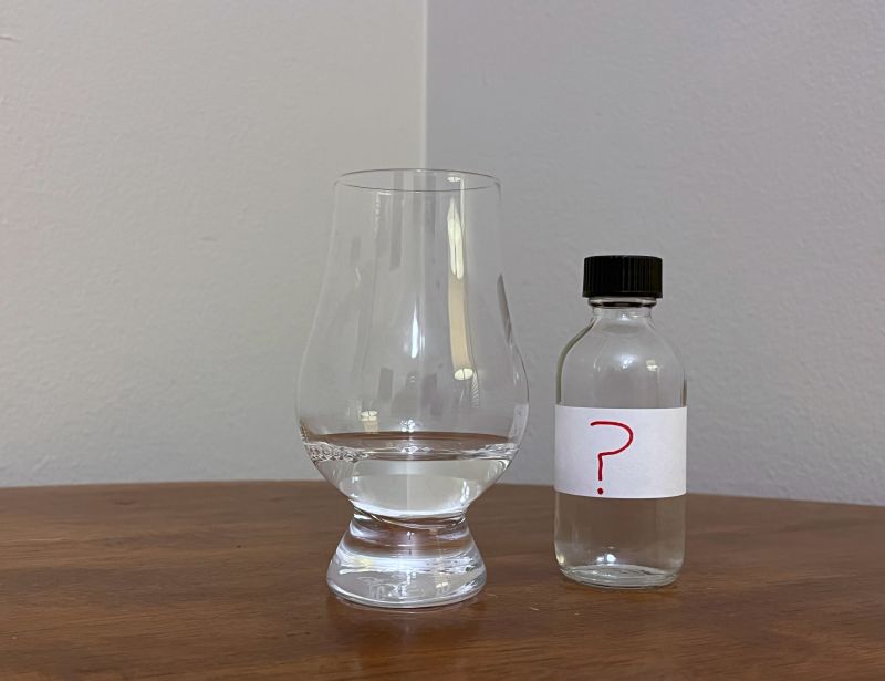 A bottle of Mystery Sample #1 next to a glass of rum