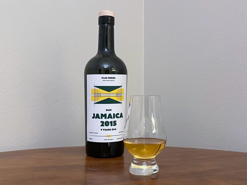 A bottle of Flag Series Jamaica 2015 9 year next to a glass of rum