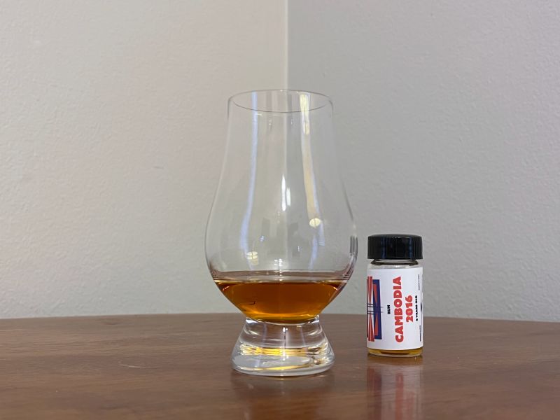 A bottle of Flag Series Cambodia 2016 8 year next to a glass of rum