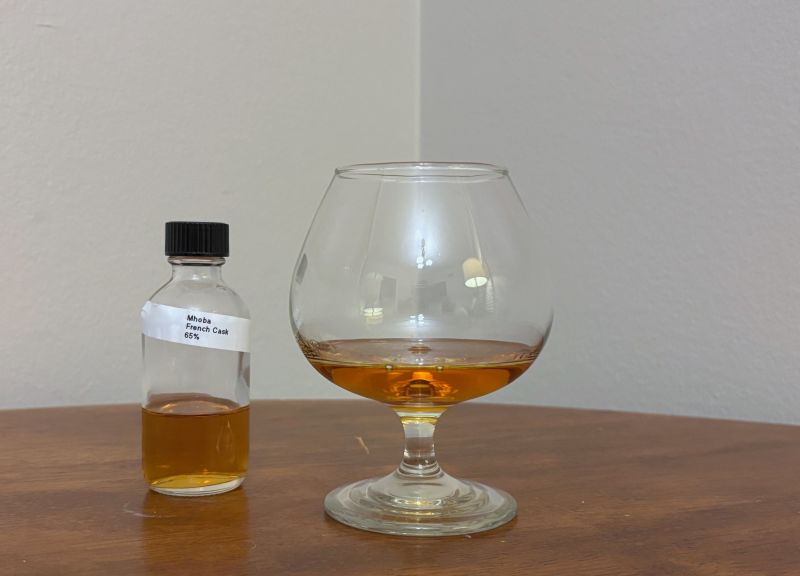 A bottle of Mhoba Select Reserve French Cask next to a glass of rum