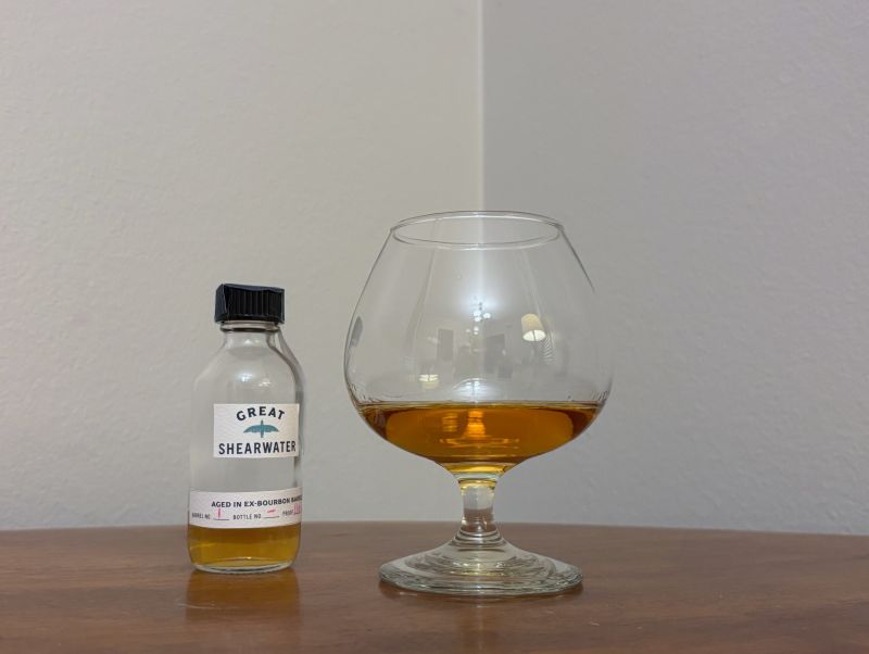 A bottle of Great Shearwater Trinidad 14 year Barrel #1 next to a glass of rum