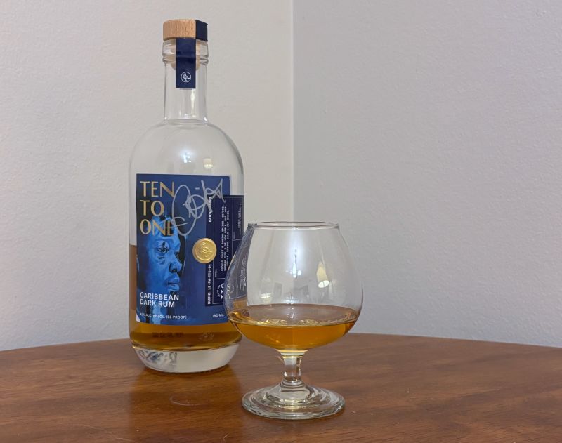 A bottle of Ten to One Caribbean Dark Rum next to a glass of rum