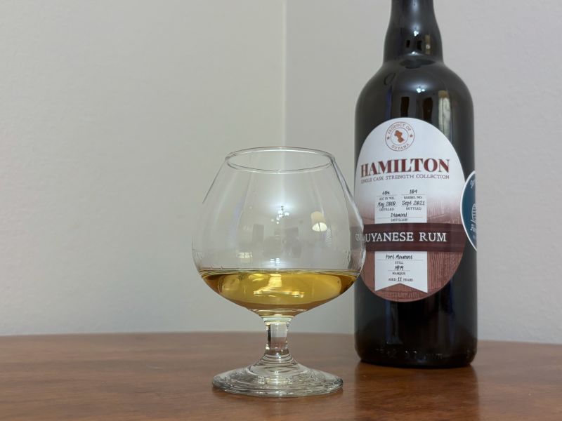 A bottle of Hamilton Single Cask Port Mourant next to a glass of rum