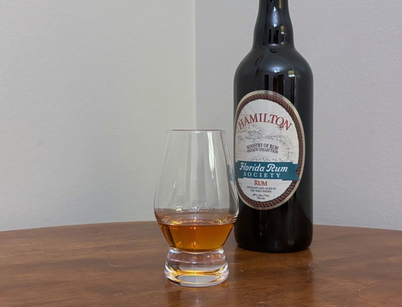 A bottle of Hamilton Florida Rum Society Blend next to a glass of rum
