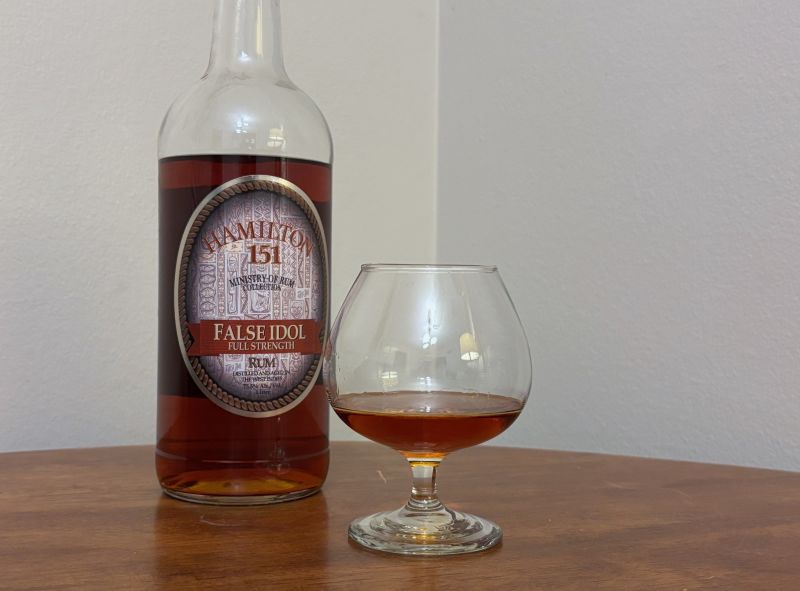 A bottle of Hamilton 151 False Idol Edition next to a glass of rum