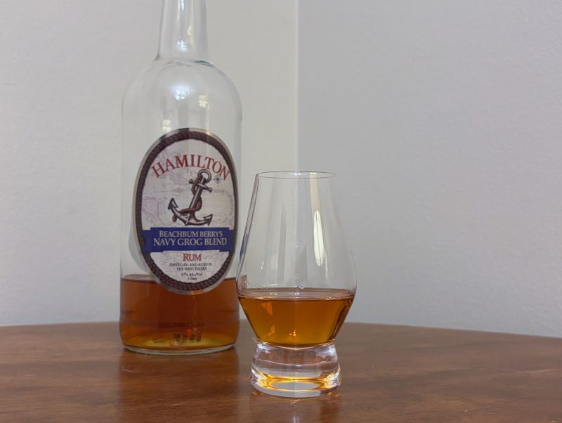 A bottle of Hamilton Beachbum Berry's Navy Grog Blend next to a glass of rum