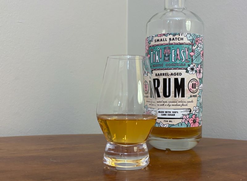 A bottle of Tiki Easy Barrel-Aged Rum next to a glass of rum