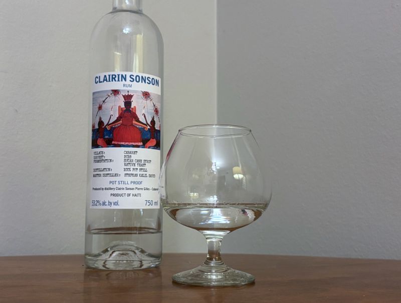 A bottle of Clairin Sonson next to a glass of rum