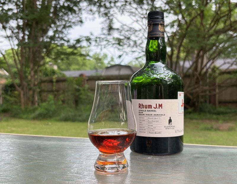 A bottle of Rhum JM Single Barrel - Elemental Spirits next to a glass of rum
