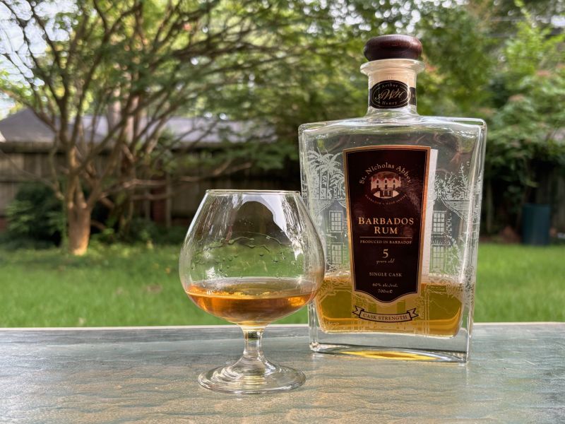A bottle of St. Nicholas Abbey 5 year Cask Strength next to a glass of rum