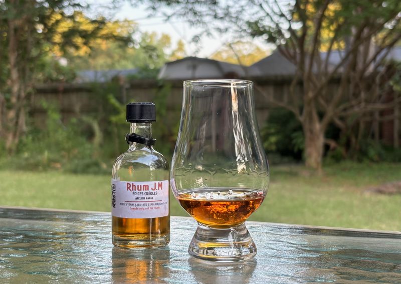 A bottle of Rhum JM Épices Crêoles next to a glass of rum