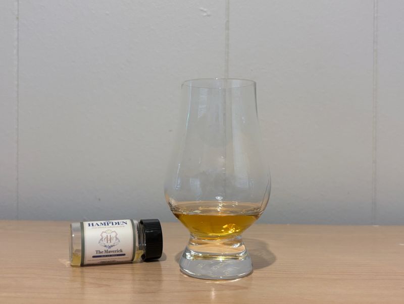 A bottle of Hampden Estate The Maverick next to a glass of rum