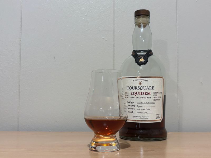 A bottle of Foursquare Equidem next to a glass of rum