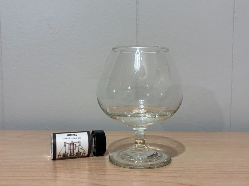 A bottle of Habitation Velier Mhoba Unaged next to a glass of rum