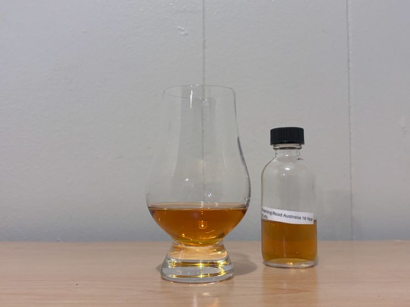 A bottle of Roaming Road Australia 16 year next to a glass of rum