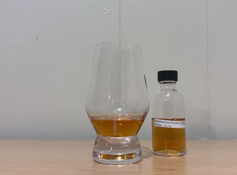 A bottle of Roaming Road Guyana 12 year next to a glass of rum