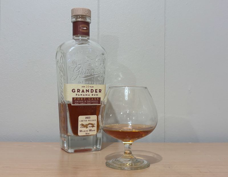 A bottle of Grander Port Cask Finish 10 year next to a glass of rum
