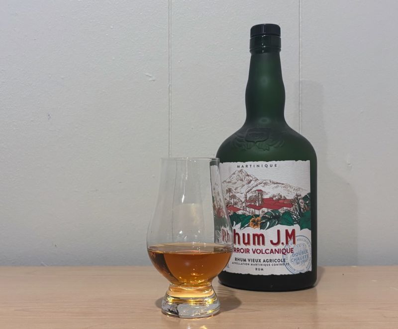 A bottle of Rhum JM Terroir Volcanique next to a glass of rum