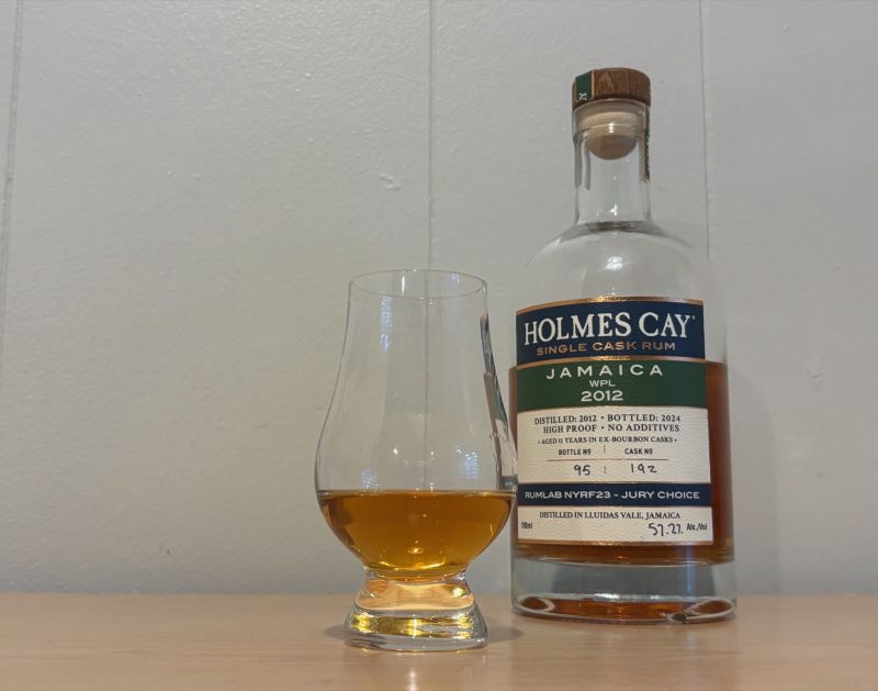 A bottle of Holmes Cay Jamaica WPL 2012 next to a glass of rum