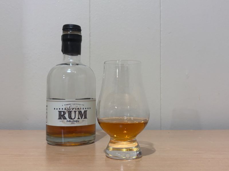 A bottle of Krewe Exclusive Barrel Finished Rum #3 next to a glass of rum