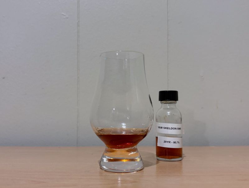 A bottle of Valinch & Mallet Skeldon SWR 20 Year next to a glass of rum