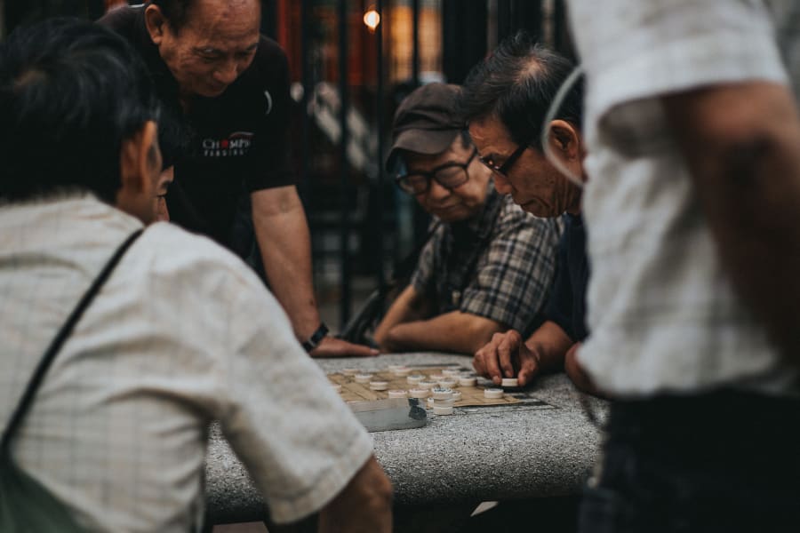 Intimate photograph of men playing and watching a checkers game at The Five Points in Chinatown, Manhattan