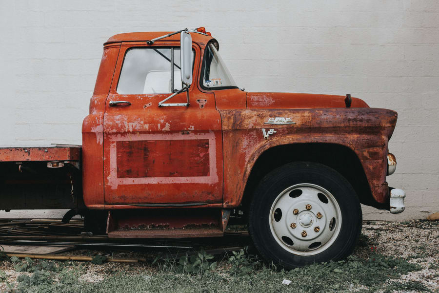 Side view of a big red tow truck against a white brick wall in Williamsburg