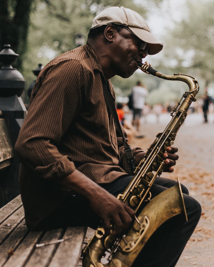 Street performer playing saxophone on a bench in central park