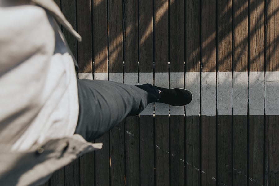 Looking down at feet walking over the wooden beams on Brooklyn Bridge